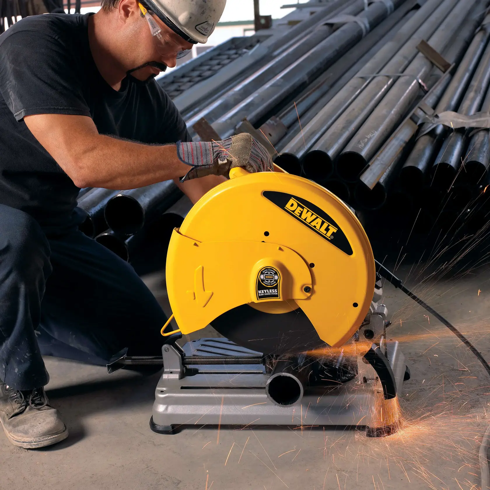 Eine Person mit Arbeitshandschuhen benutzt eine gelbe DEWALT D28715 Metalltrennsäge in einer industriellen Umgebung. Funken fliegen von der Säge, während sie ein Metallrohr schneidet, und im Hintergrund sind Stapel von Metallrohren zu sehen.