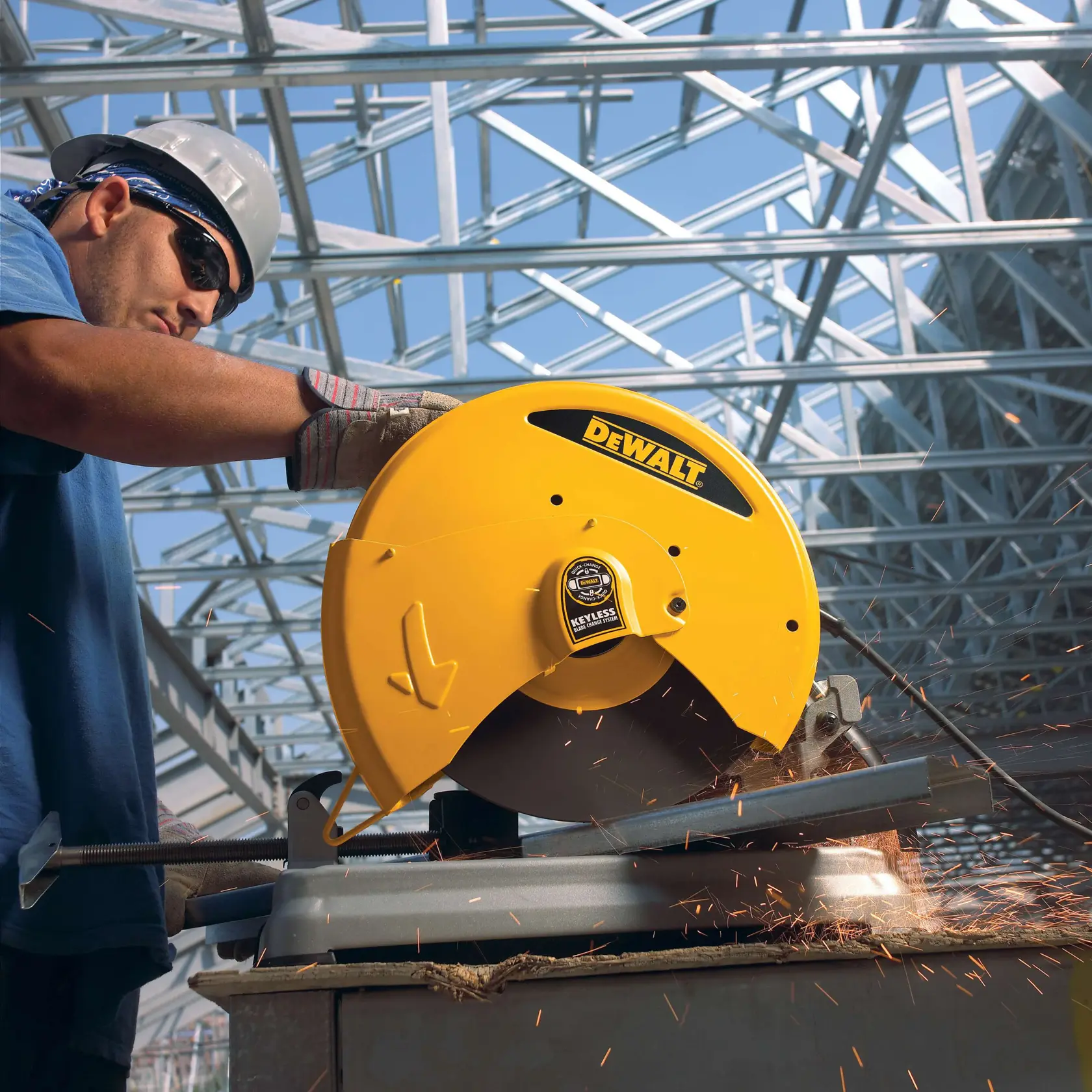 Ein Arbeiter verwendet eine gelbe DEWALT D28715 Metallsäge, um eine Metallstange zu schneiden, während Funken fliegen. Die Szene findet auf einer Baustelle mit Stahlträgern im Hintergrund statt.