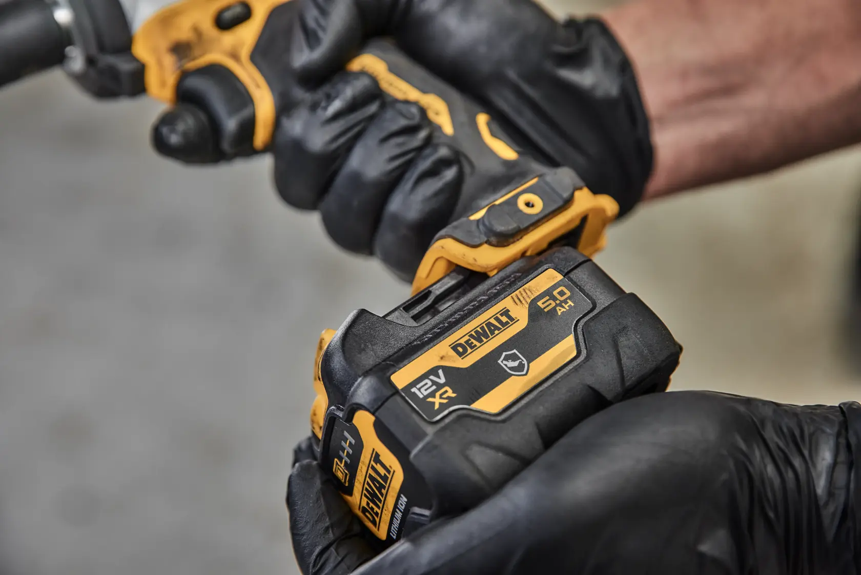 Close-up image of a DEWALT 12V MAX lithium-ion battery with a capacity of 5 amp-hours. The battery is black and yellow, featuring the DEWALT logo, battery status indicator, and technical specifications.