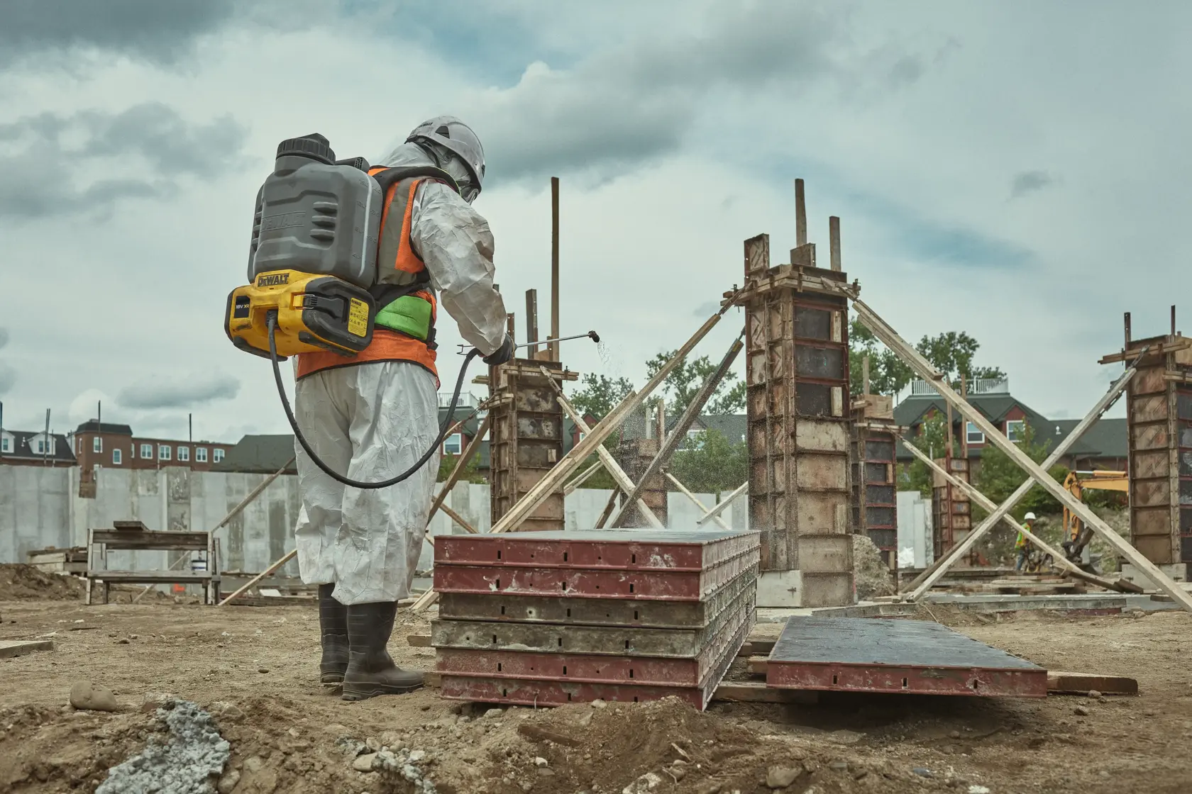 Ouvrier avec DEWALT DCCS1100N-XJ, DCCS1100N sur chantier, équipé et utilisant un pulvérisateur.