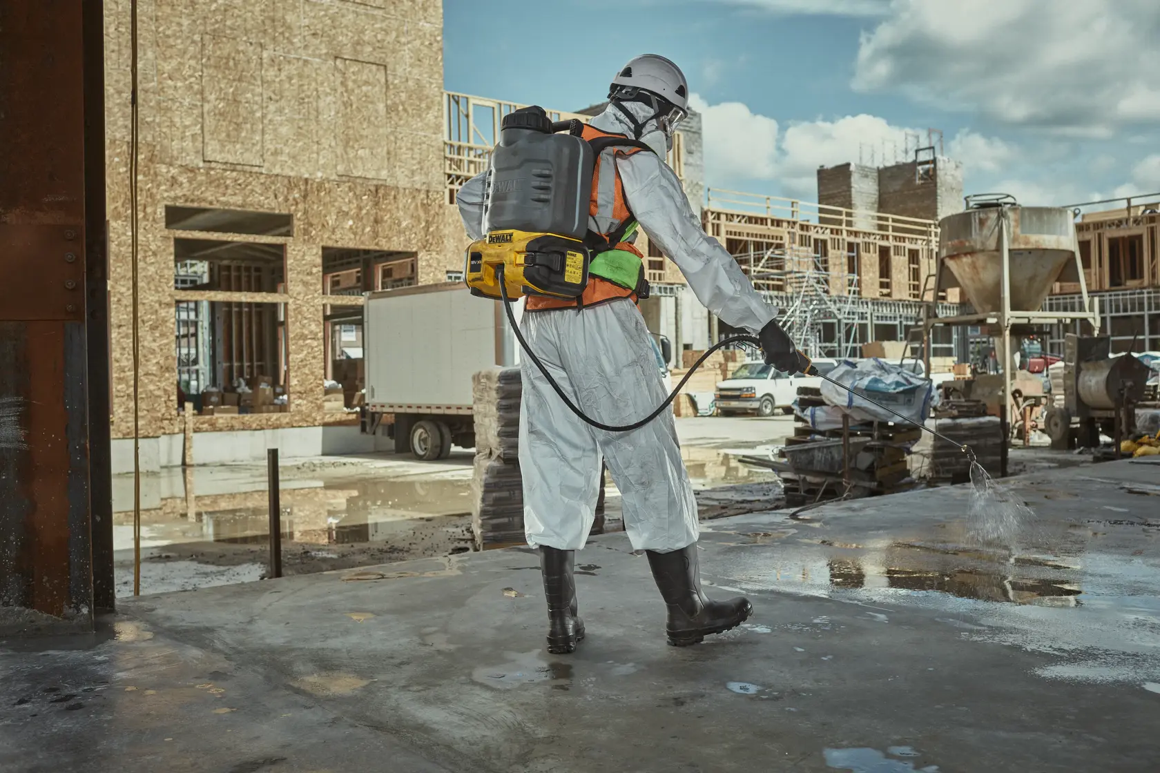 DEWALT DCCS1100N-XJ, DCCS1100N sur chantier. Travailleur pulvérise surface, équipé de protections.