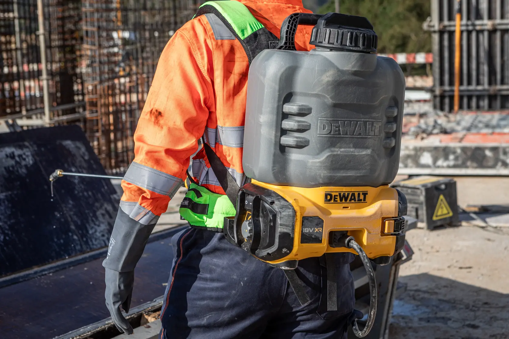 Pulvérisateur DEWALT porté sur le dos. Réf. : DCCS1100N-XJ, DCCS1100N. Utilisé dehors, tenue haute visibilité.