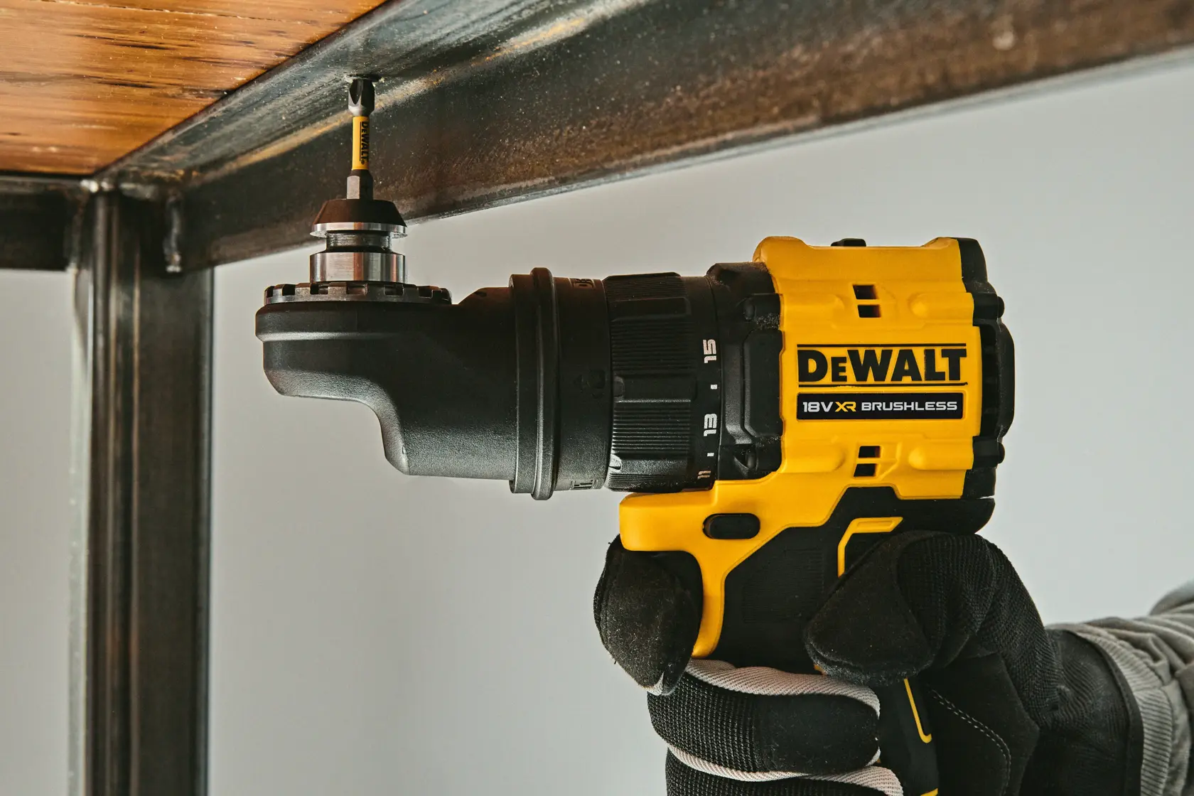 DEWALT drill with attachable heads, shown in use under a vehicle. Gloved hand holds tool for versatile applications.