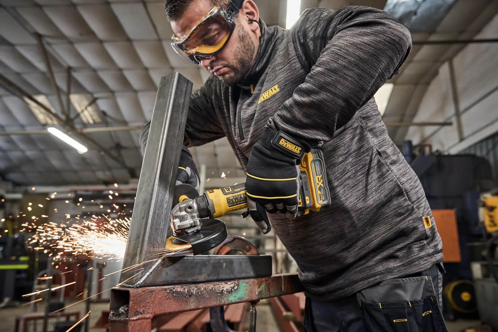 DEWALT Winkelschleifer schneidet Metall mit Funken. Arbeiter mit Handschuhen in Werkstatt.