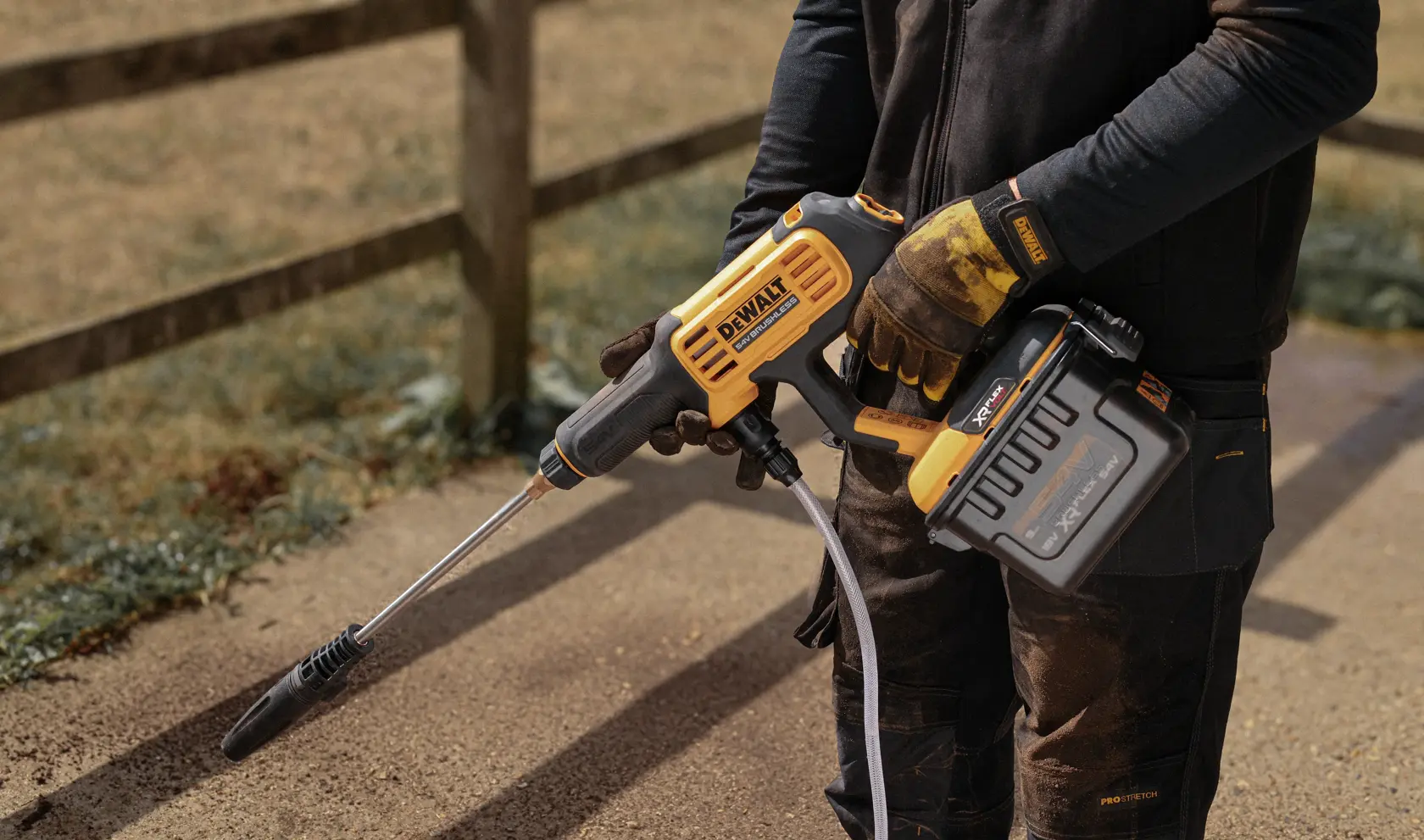 DEWALT DCMPW1000N, DCMPW1000N-XJ hidrolimpiadora inalámbrica sostenida por una persona al aire libre.