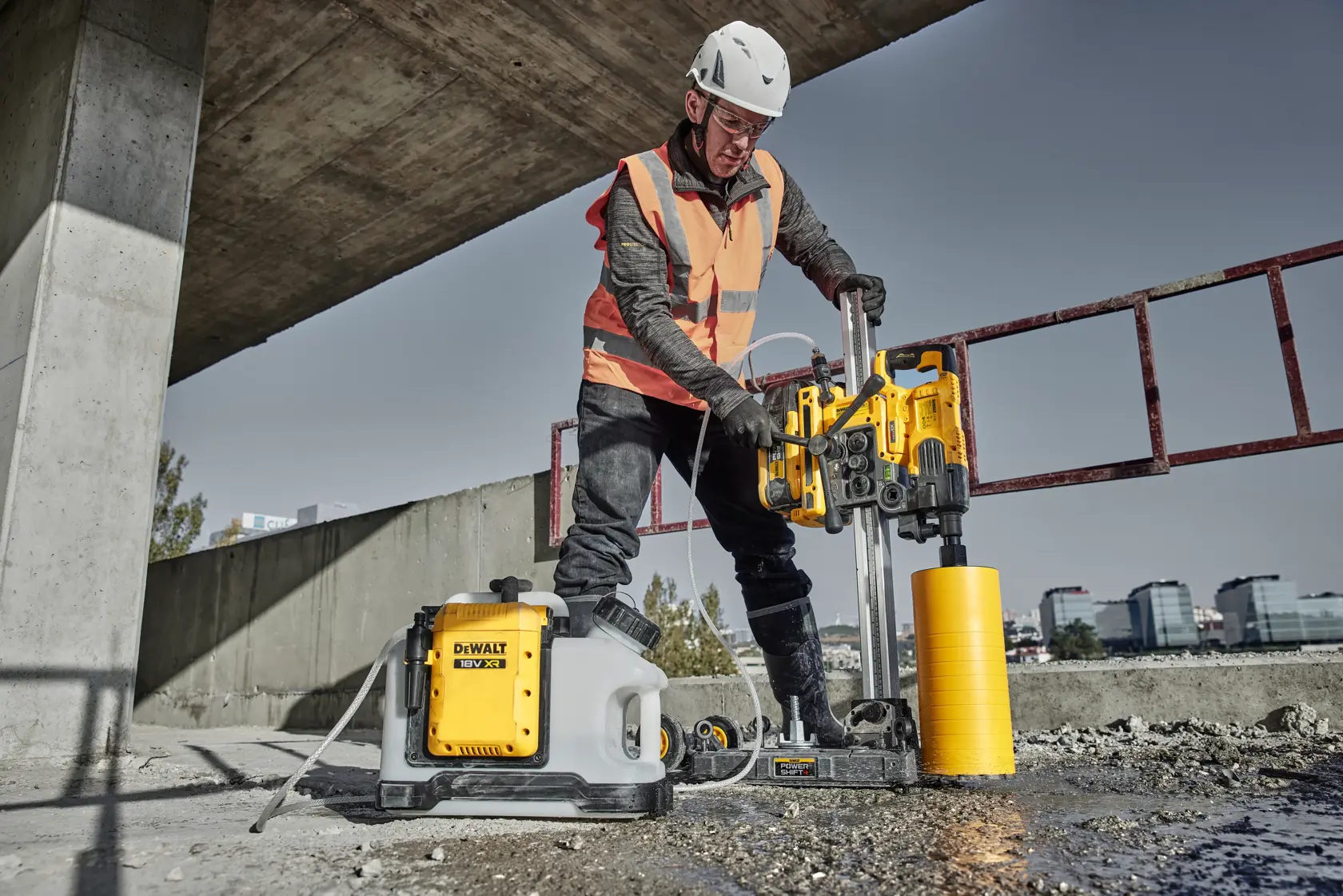 Trabajador usa perforadora DEWALT DCPS151 en concreto, con casco y chaleco de seguridad en obra.