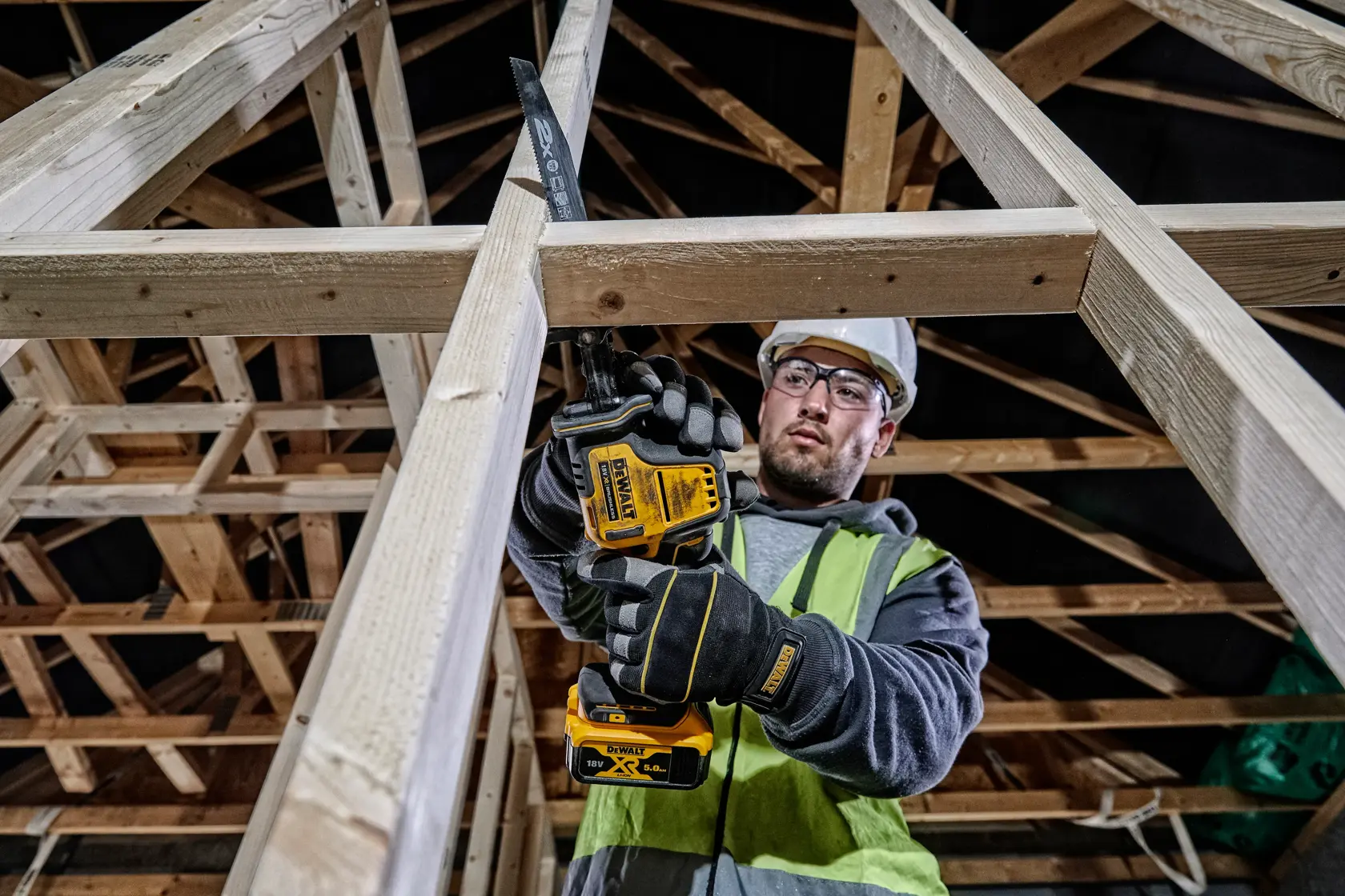 Arbeiter schneidet Holzrahmen mit DEWALT DCS369NT in einem Baugebäude.