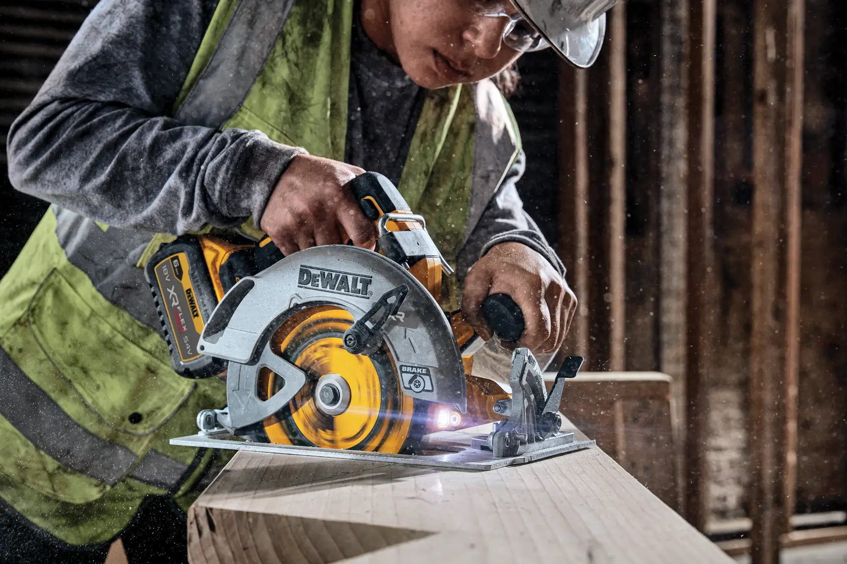 Sierra circular inalámbrica DEWALT cortando madera, usada por trabajador con chaleco en obra.