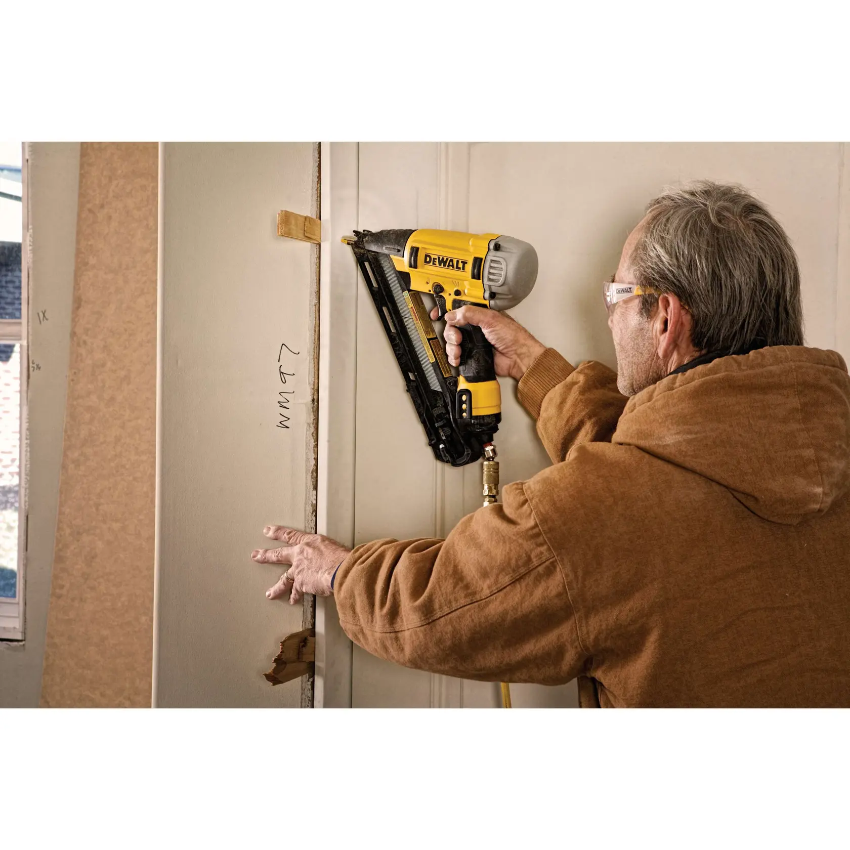 Person arbeitet mit einem DEWALT Nagler, um Zierleisten am Türrahmen während der Renovierung zu befestigen.