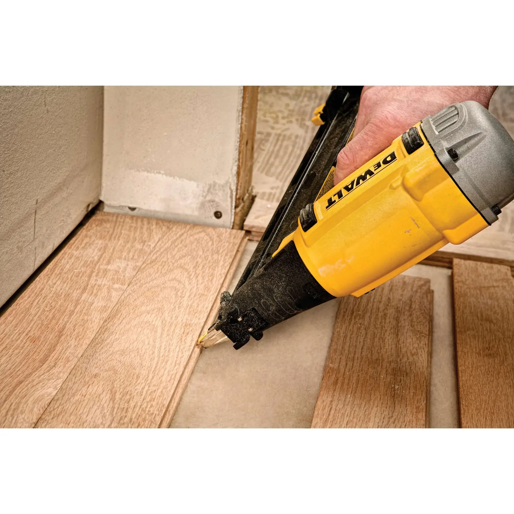 DEWALT Nagler befestigt Holzfußboden nahe einer Wand bei der Installation.