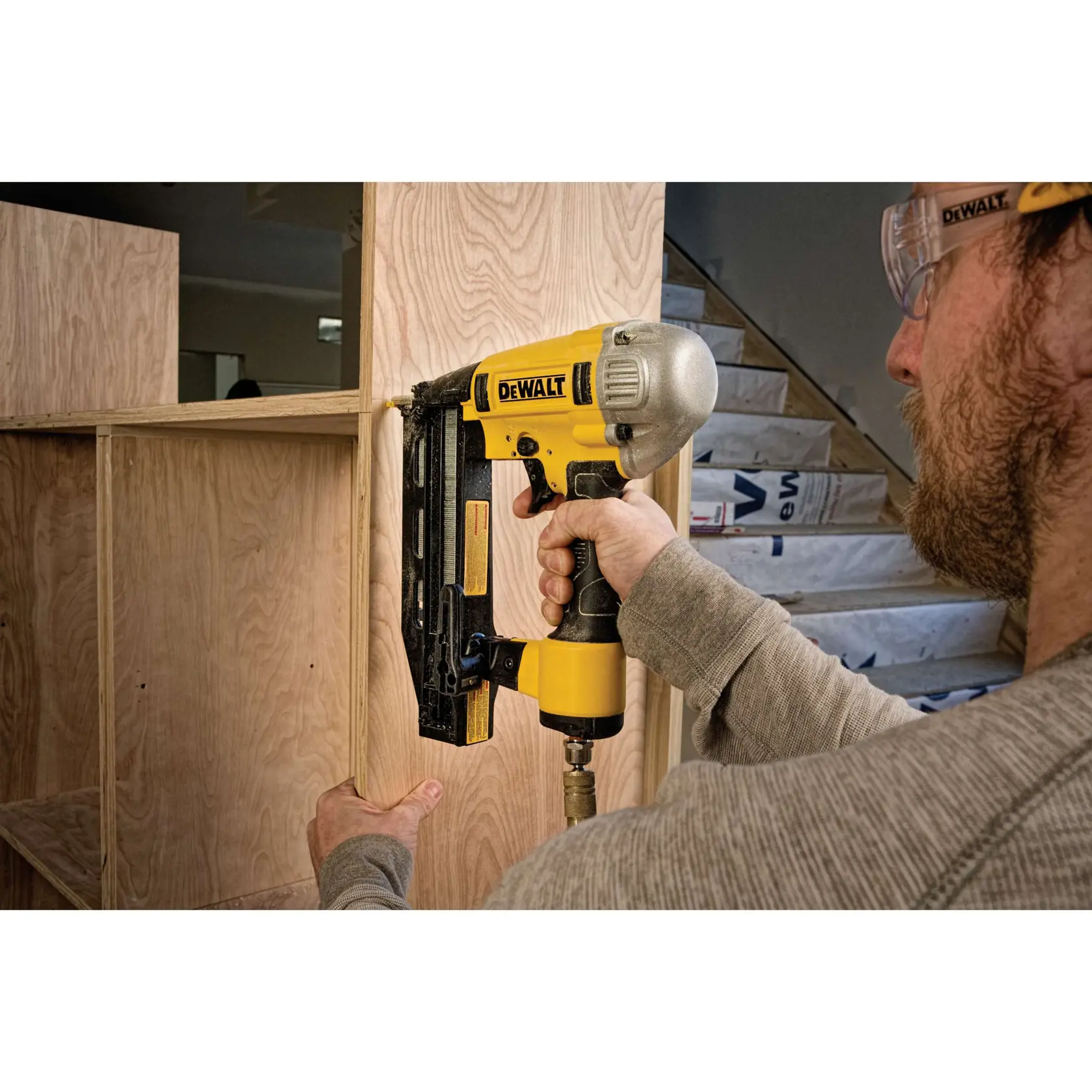Person nutzt eine DEWALT Nagelpistole, um Holzregale zu montieren.