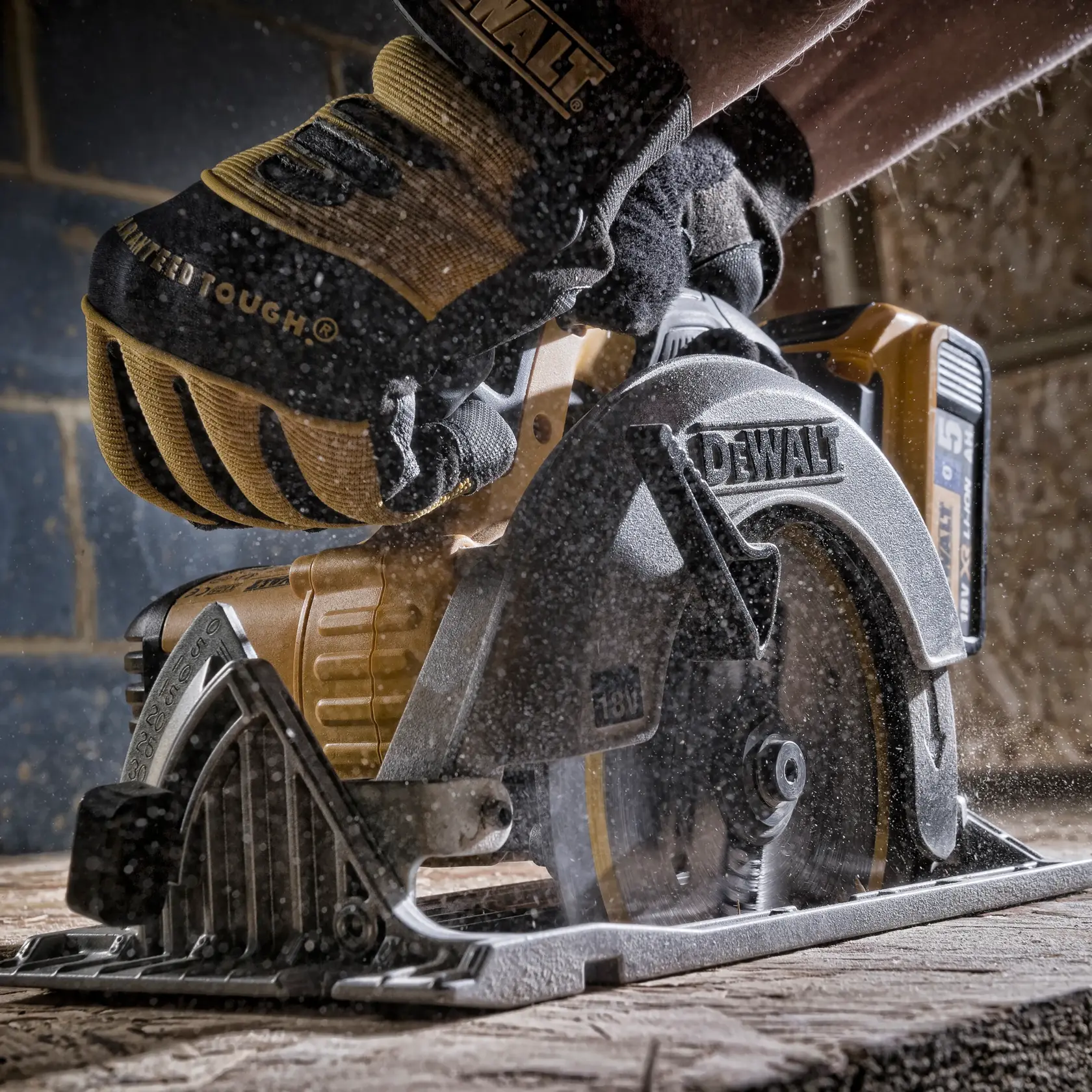 Eine behandschuhte Hand führt eine DEWALT Kreissäge und schneidet Holz in einer staubigen Werkstatt.