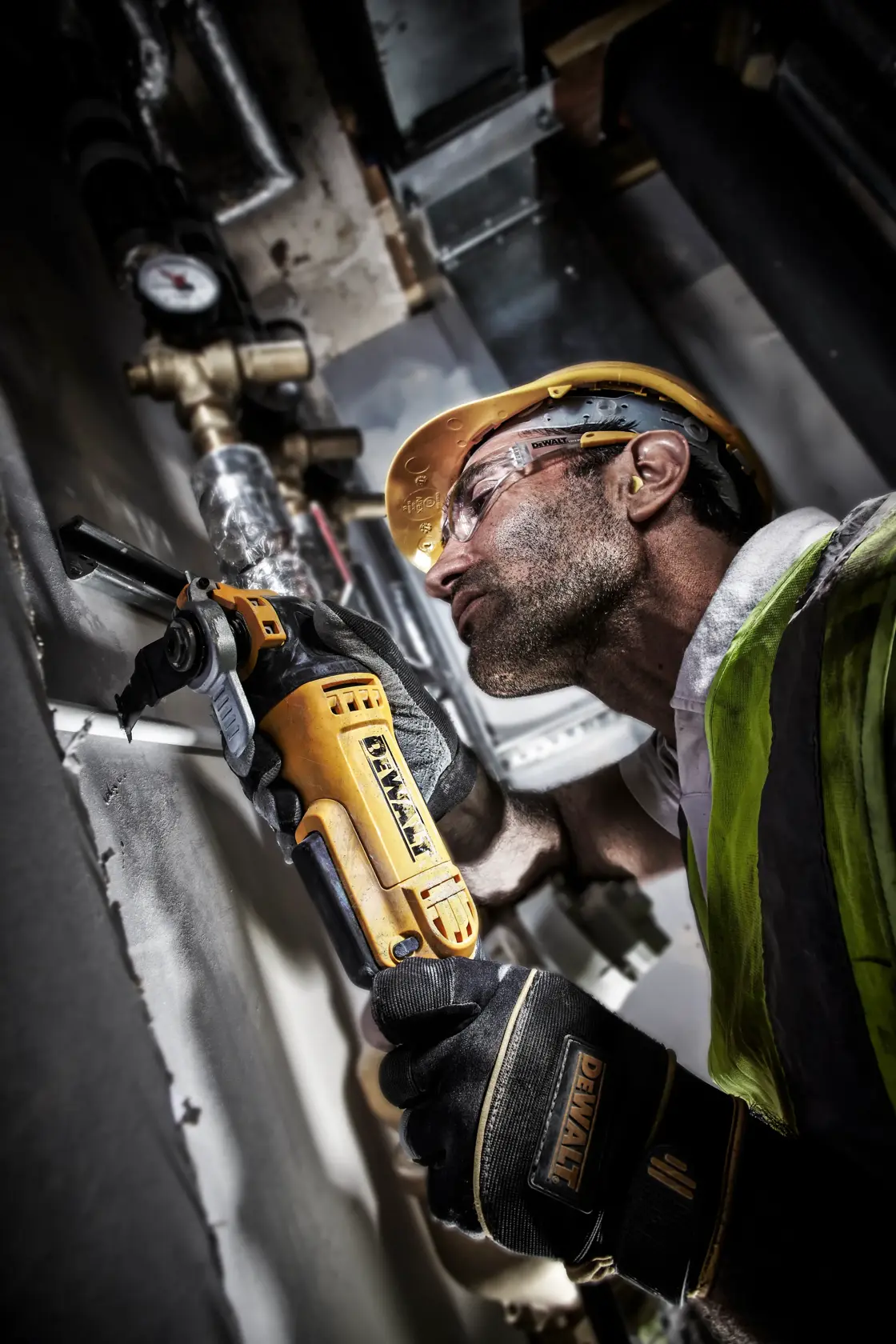 Arbeiter nutzt DEWALT DT20701 Werkzeug zum Schneiden von Metallrohren, trägt Schutzausrüstung.