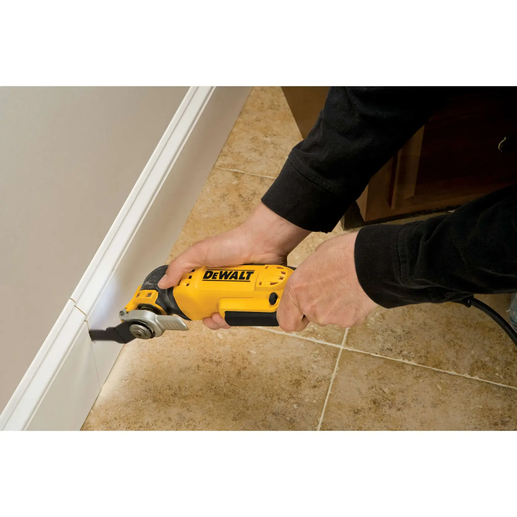 Person schneidet mit DEWALT Multitool eine Fußleiste am Fliesenboden.