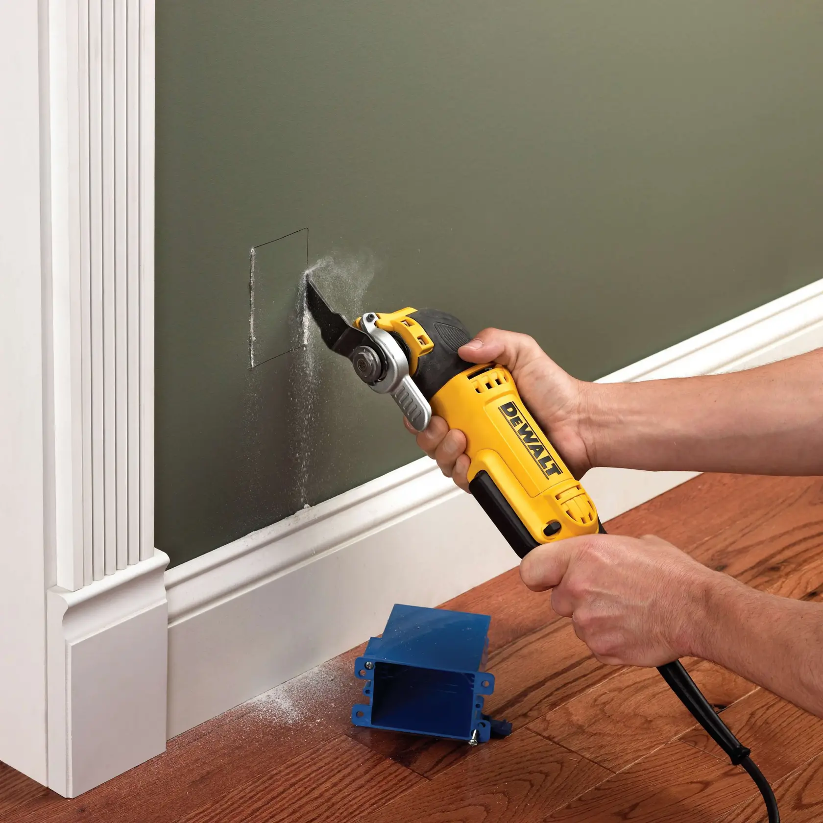 DEWALT-Werkzeug schneidet ein Loch in eine Wand, blaue Box und Sägemehl sind sichtbar.