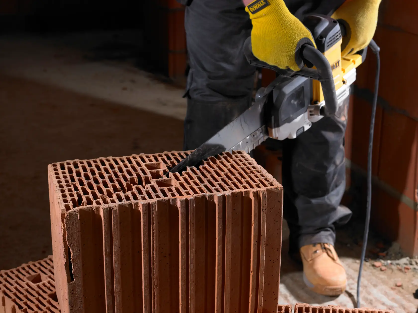 Person schneidet mit einer DEWALT Säge einen Hohlziegel auf einer Baustelle.