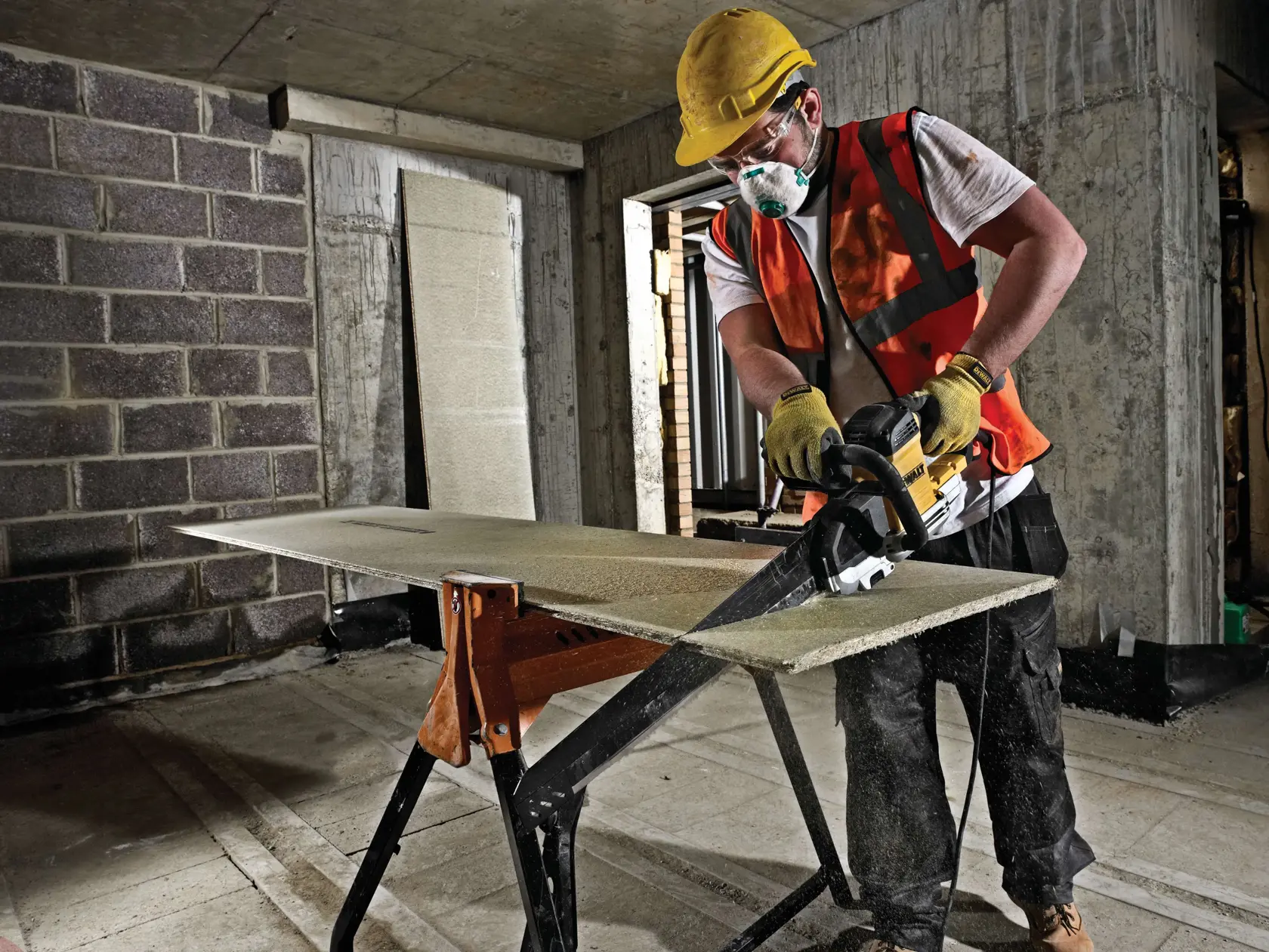 Arbeiter sägt Brett mit DEWALT Säge auf Baustelle und trägt Schutzausrüstung.