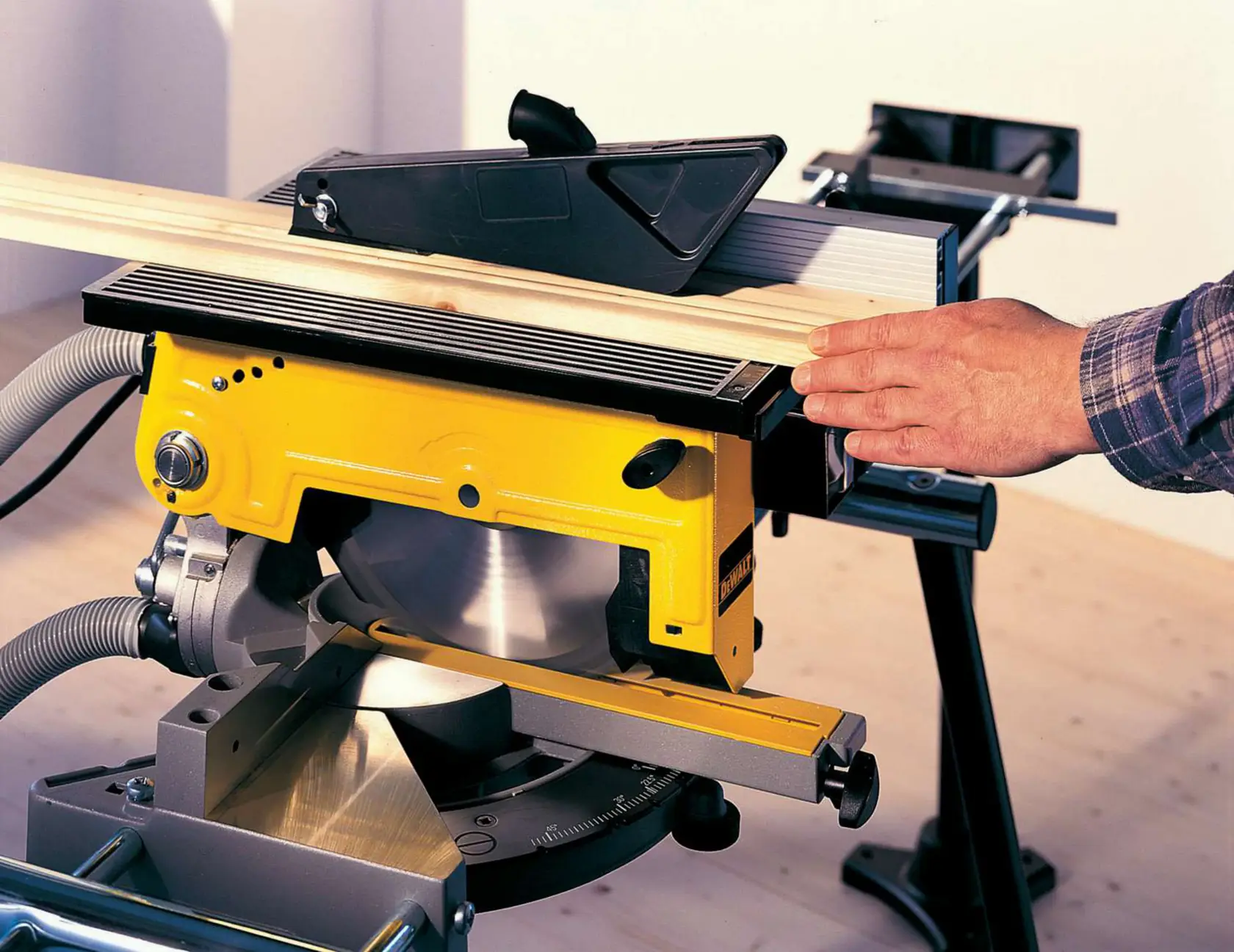 Gelbe DEWALT Tischsäge wird drinnen auf einer Werkbank zum Schneiden von Holz benutzt.