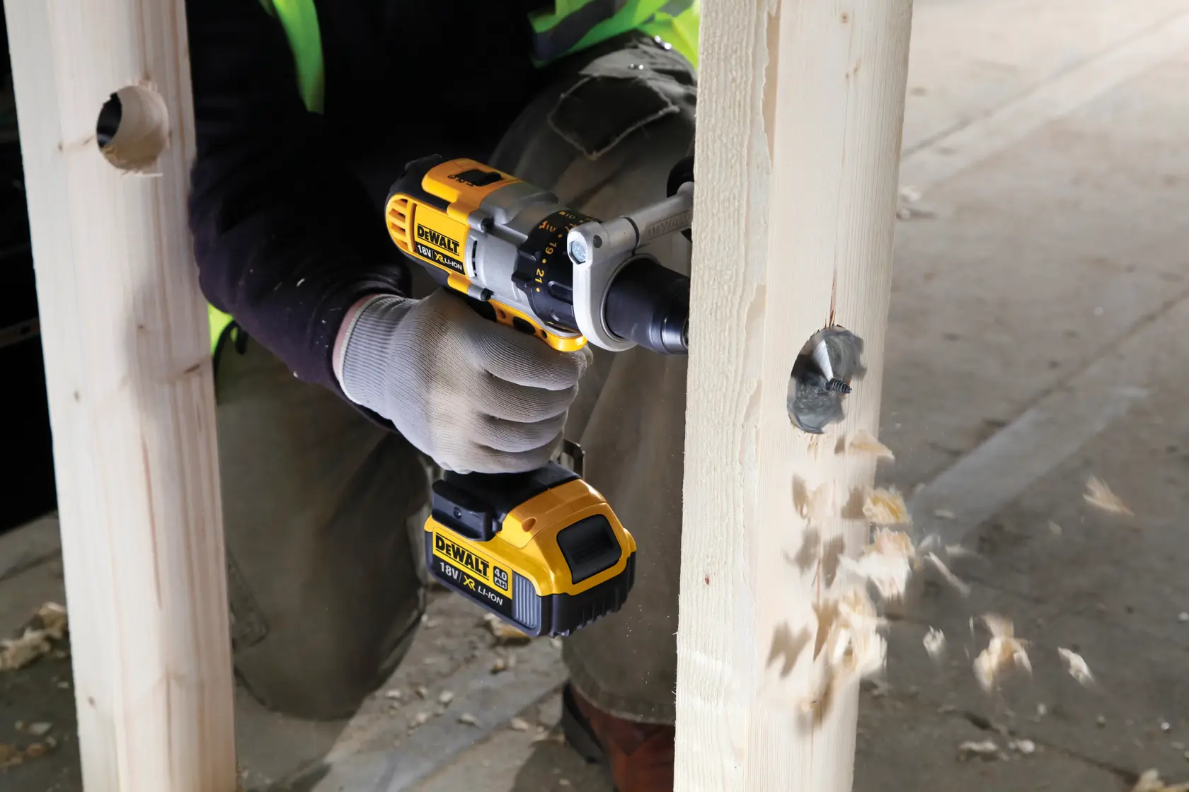 Taladro DEWALT perforando una viga de madera, virutas de madera saltan durante el proceso.