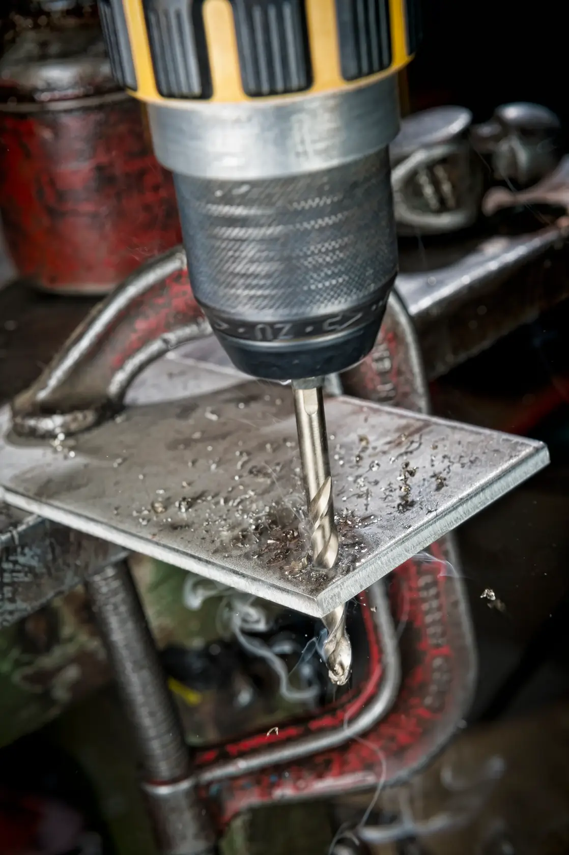 Primer plano de una broca DEWALT perforando una placa metálica, virutas de metal visibles.