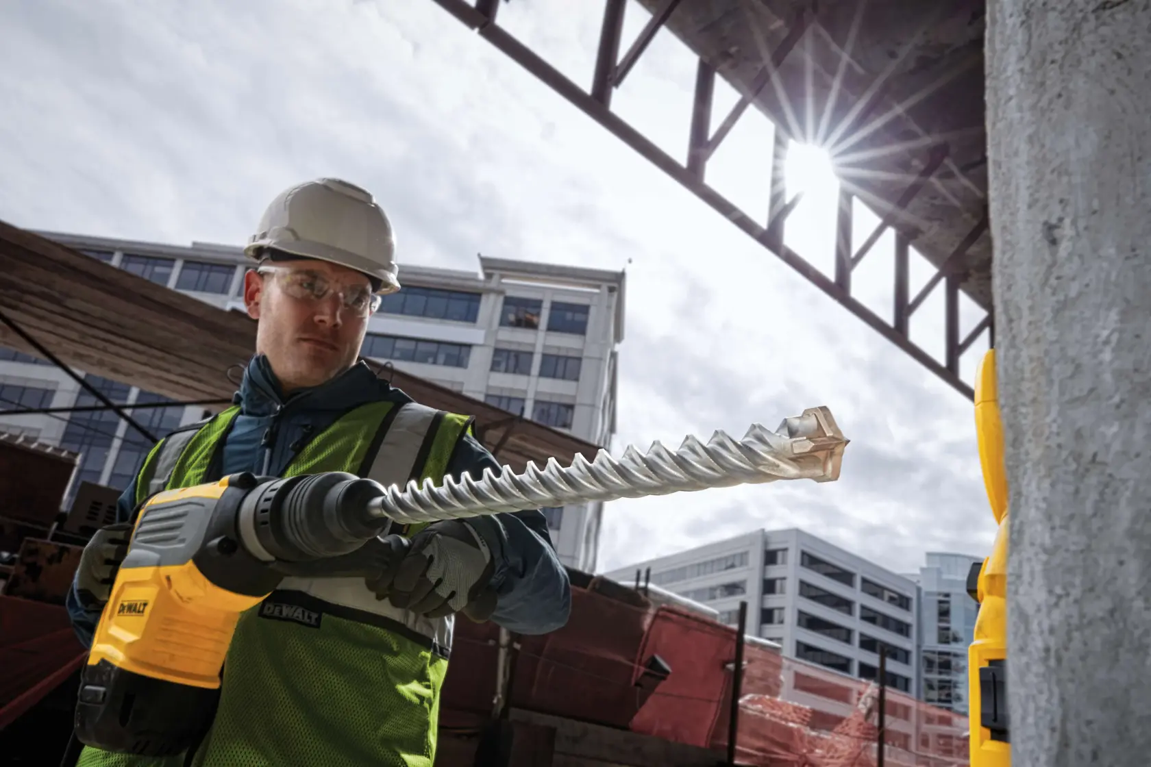 Trabajador usa taladro DEWALT con broca DT60844 en obra, con equipo de seguridad y casco.