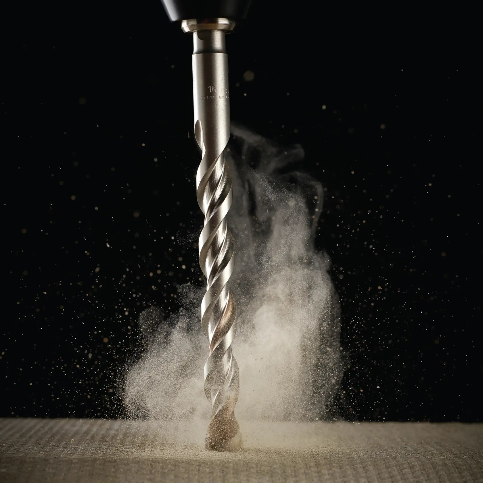 Broca DEWALT perforando material, polvo levantándose, primer plano sobre fondo oscuro.