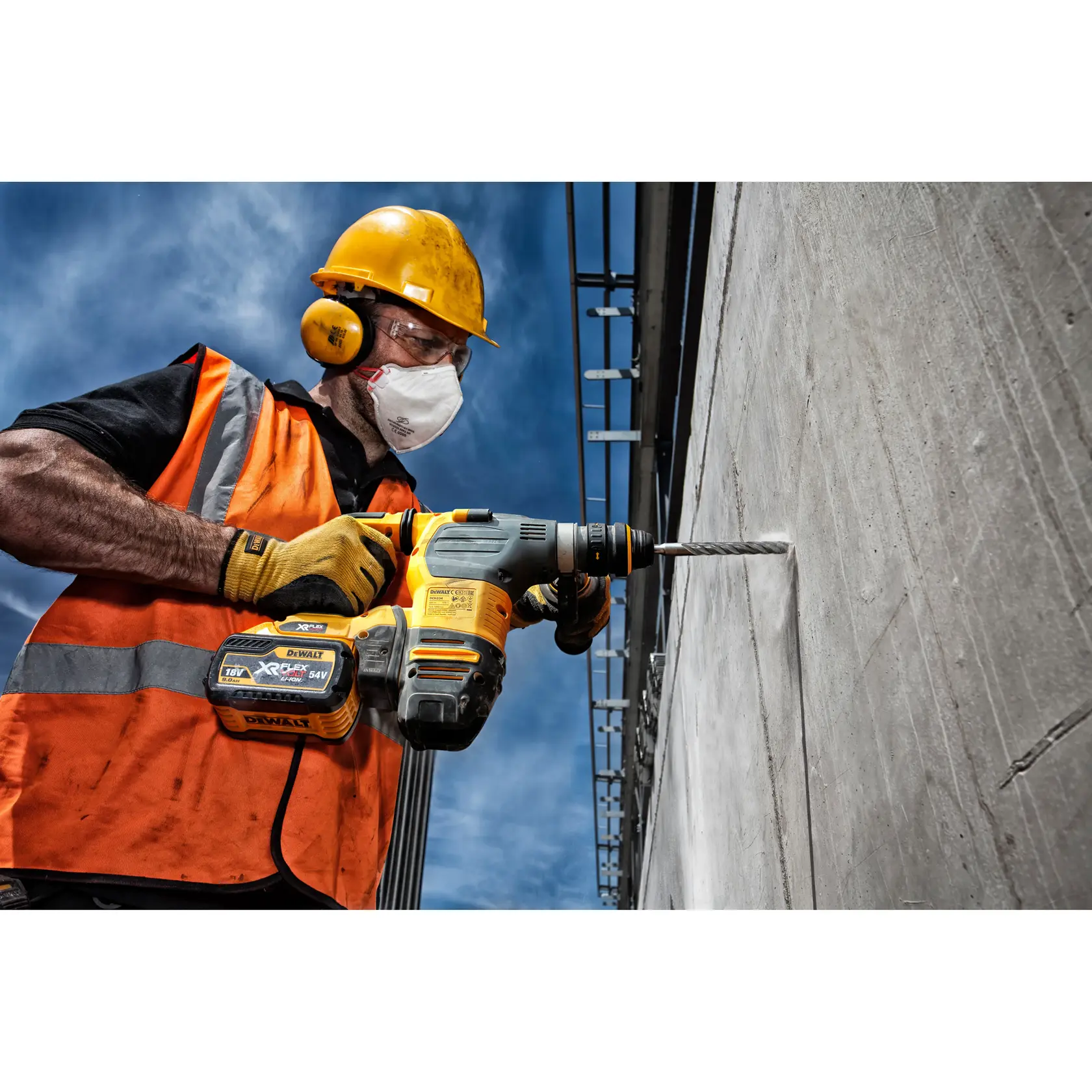 Persona perforando pared de concreto con DEWALT DT9504, usando chaleco naranja y casco de seguridad.