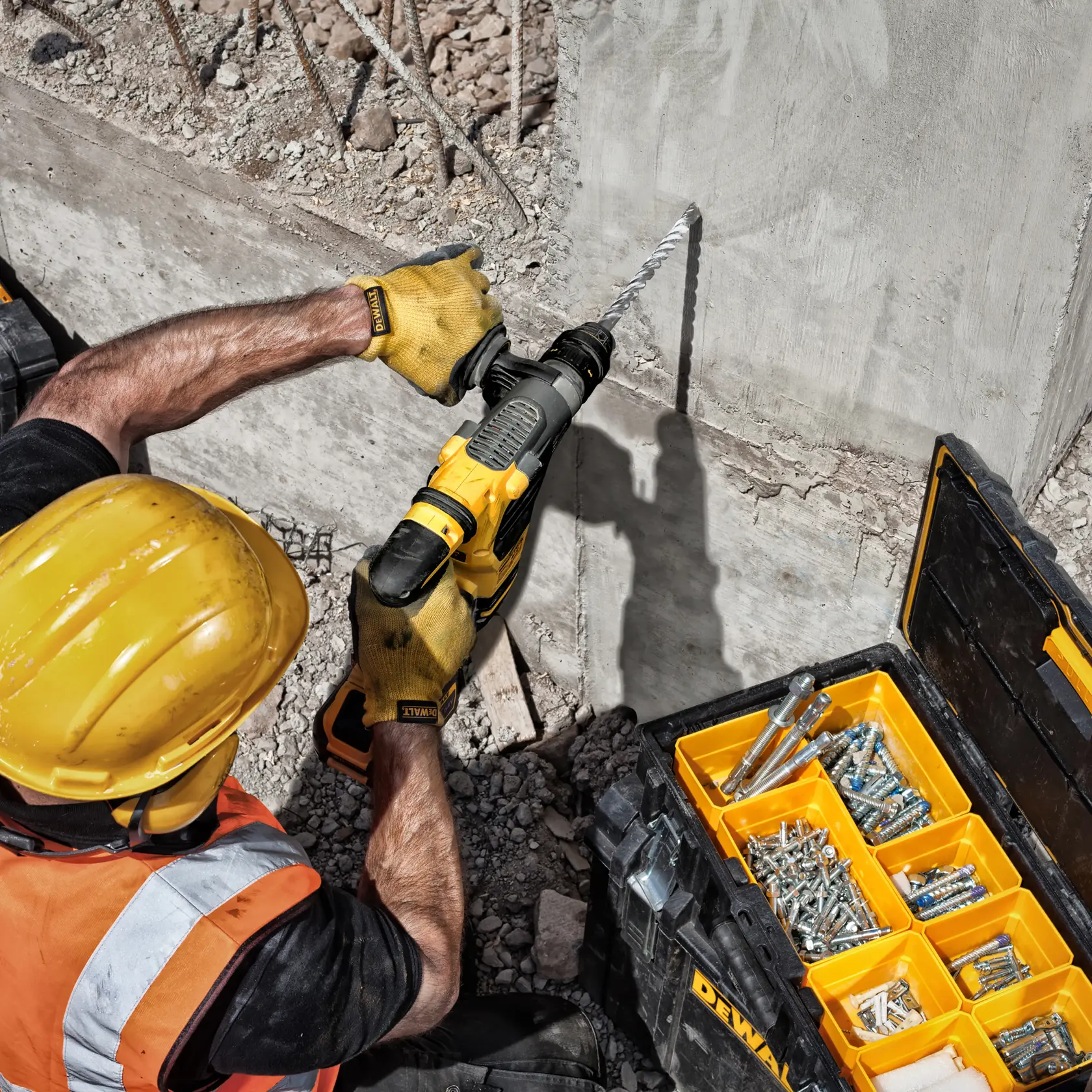Trabajador perfora concreto con brocas DEWALT DT9580, DT9580-QZ. Caja de herramientas cercana.
