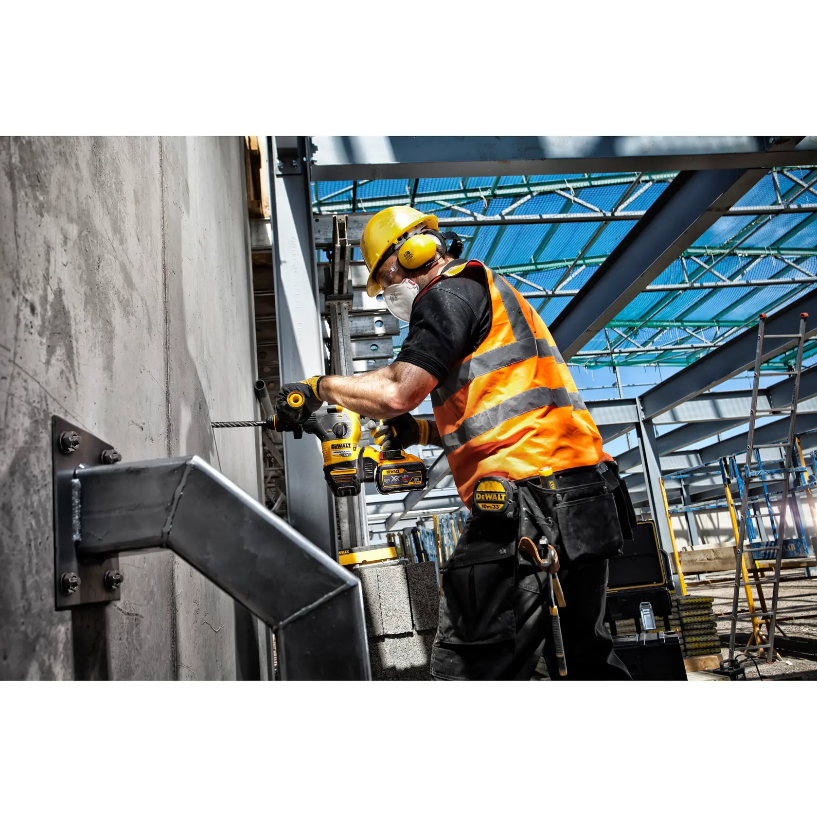 Trabajador usa taladro DEWALT en pared de concreto, con equipo de seguridad y chaleco naranja.
