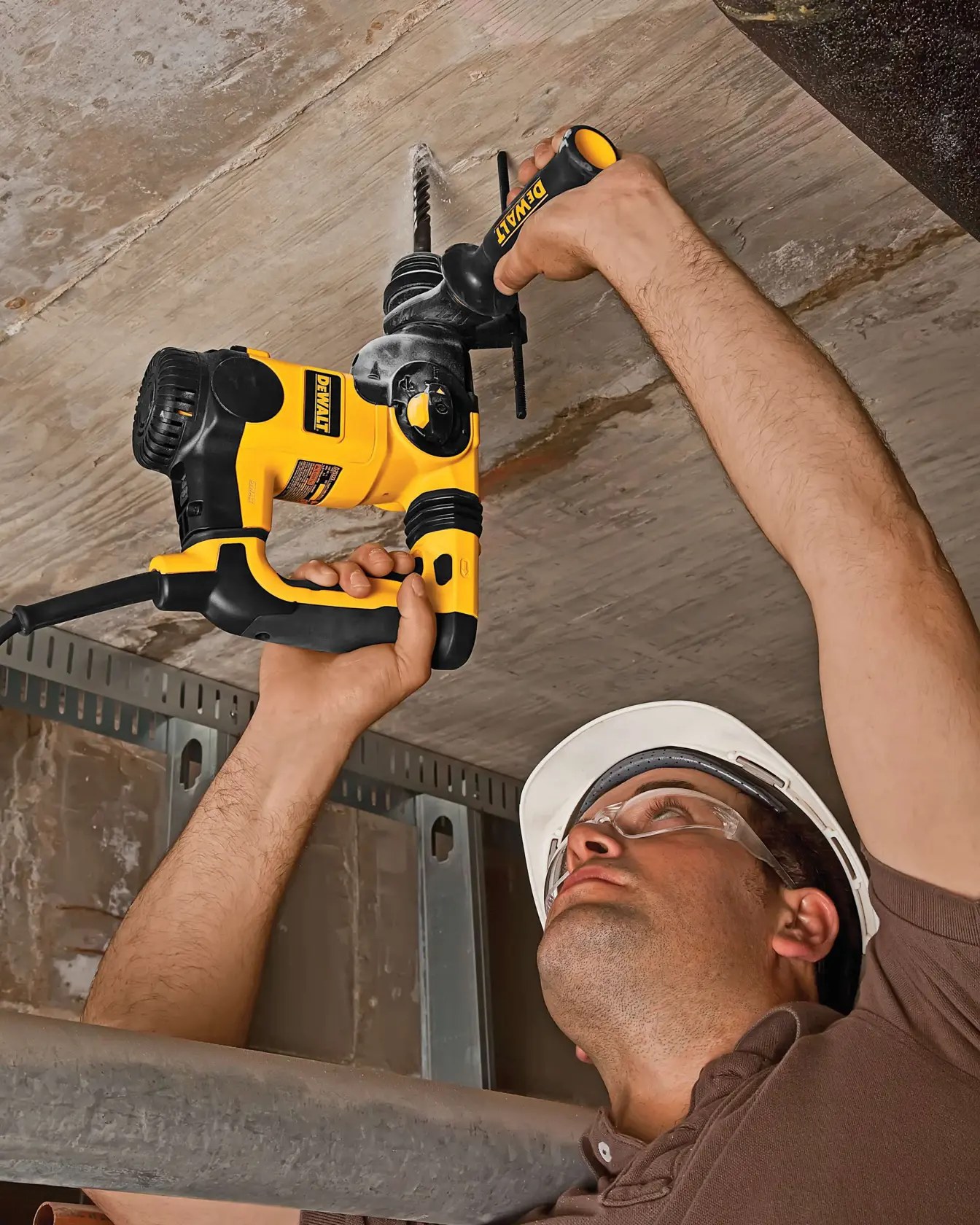 Persona taladra el techo con un taladro DEWALT amarillo y negro, usando casco protector.