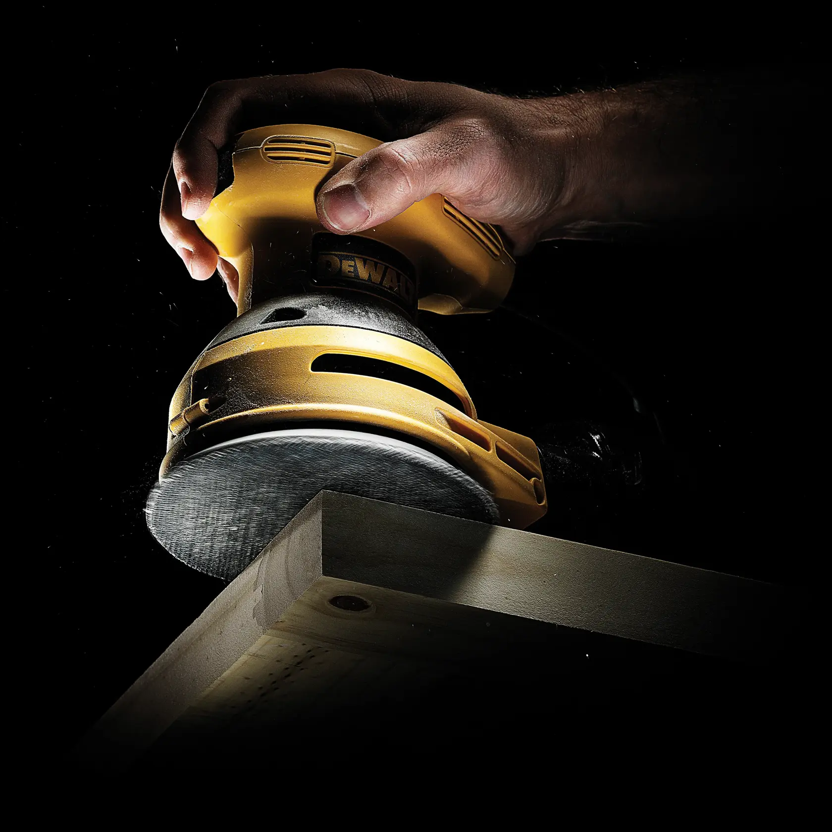 Hand arbeitet mit DEWALT Schleifmaschine an Holzbrett, Werkzeug und Schleifvorgang sichtbar.