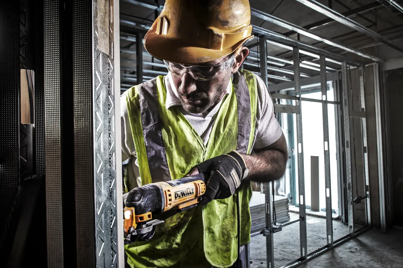 Arbeiter nutzt DEWALT DWE315 Multitool an Metallstruktur auf Baustelle. Gesicht aus Datenschutzgründen unscharf.