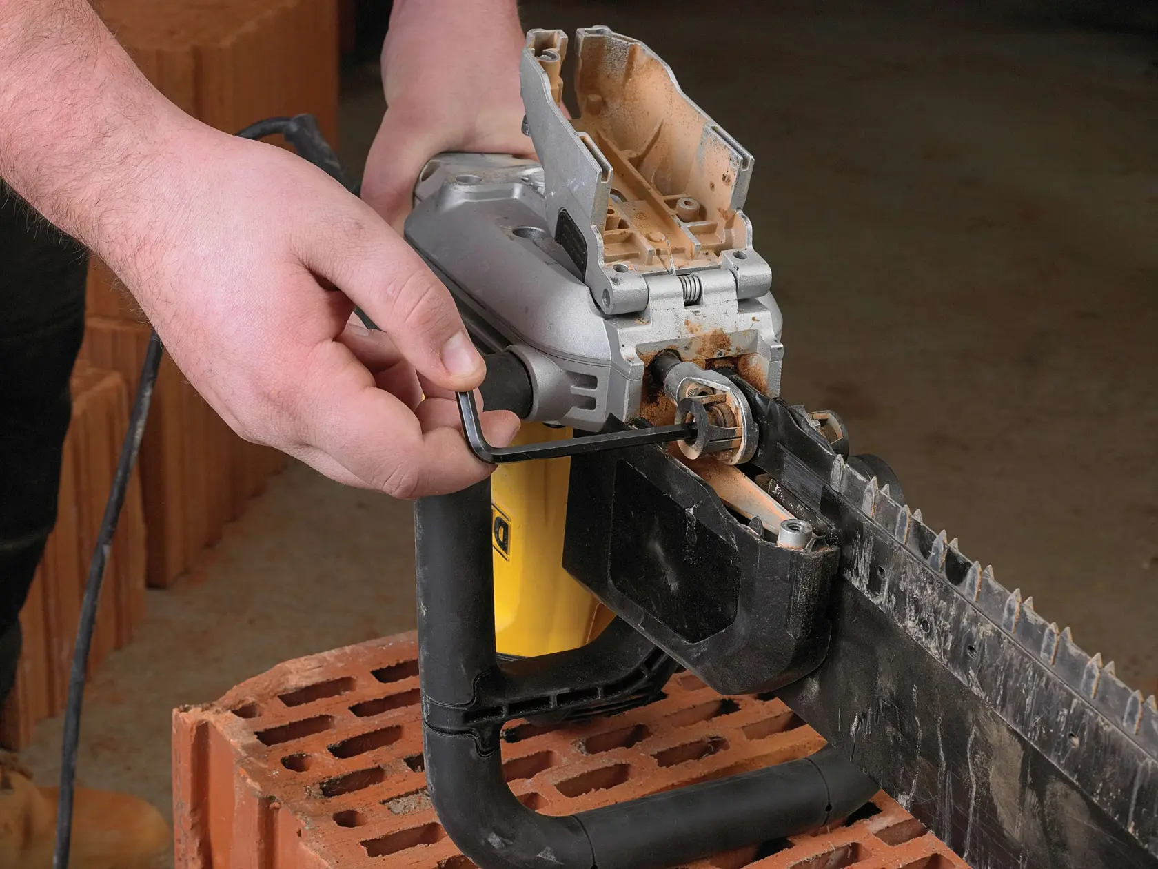 Person stellt eine DEWALT elektrische Steinsäge auf einem Ziegel mit einem Inbusschlüssel ein.
