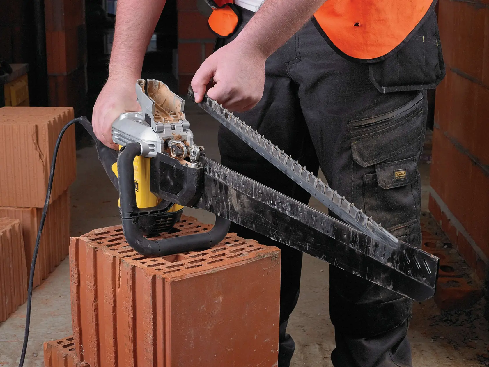 Person schneidet einen großen Tonziegel mit einer DEWALT elektrischen Steinsäge auf einer Baustelle.