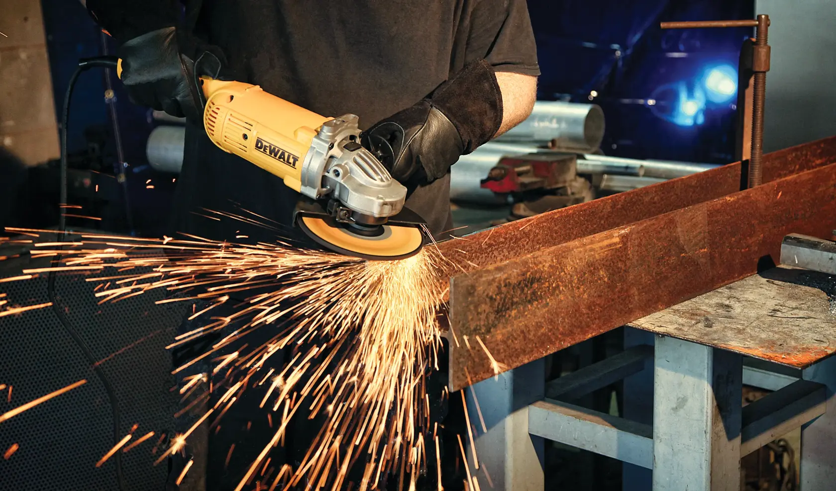 Eine Person verwendet einen DEWALT-Winkelschleifer, um einen großen Metallträger zu schneiden, wobei im Industriearbeitsbereich helle Funken entstehen.