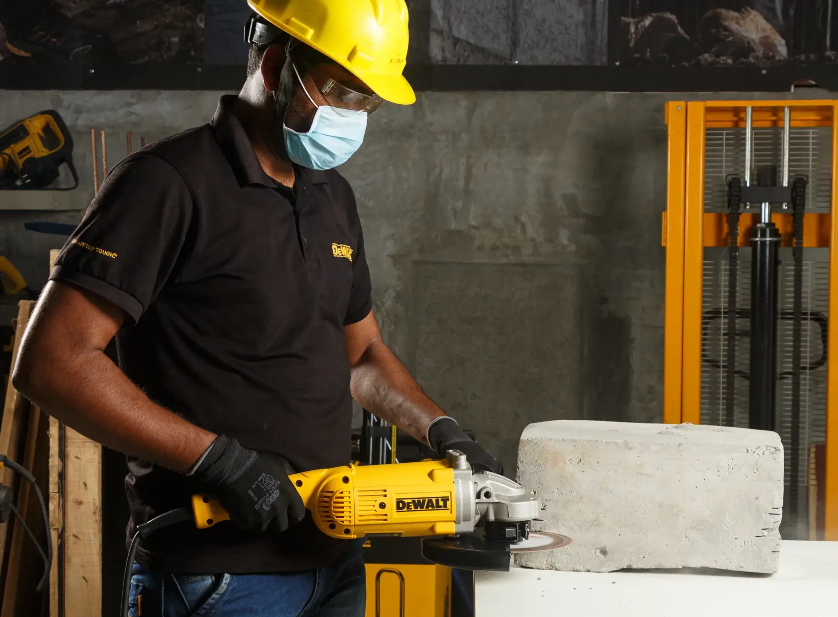 DEWALT DWE496, DWE496-QS Schleifer wird vom Arbeiter mit Schutzausrüstung an Beton genutzt.