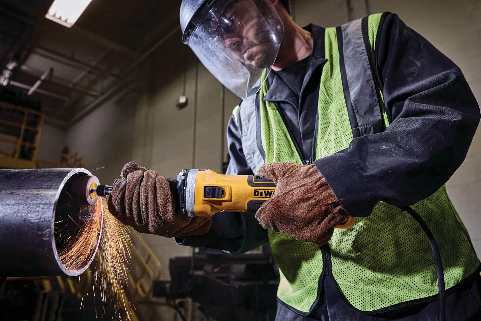 Arbeiter benutzt DEWALT Winkelschleifer zum Schneiden von Metallrohr, Funken fliegen, trägt Schutzkleidung.