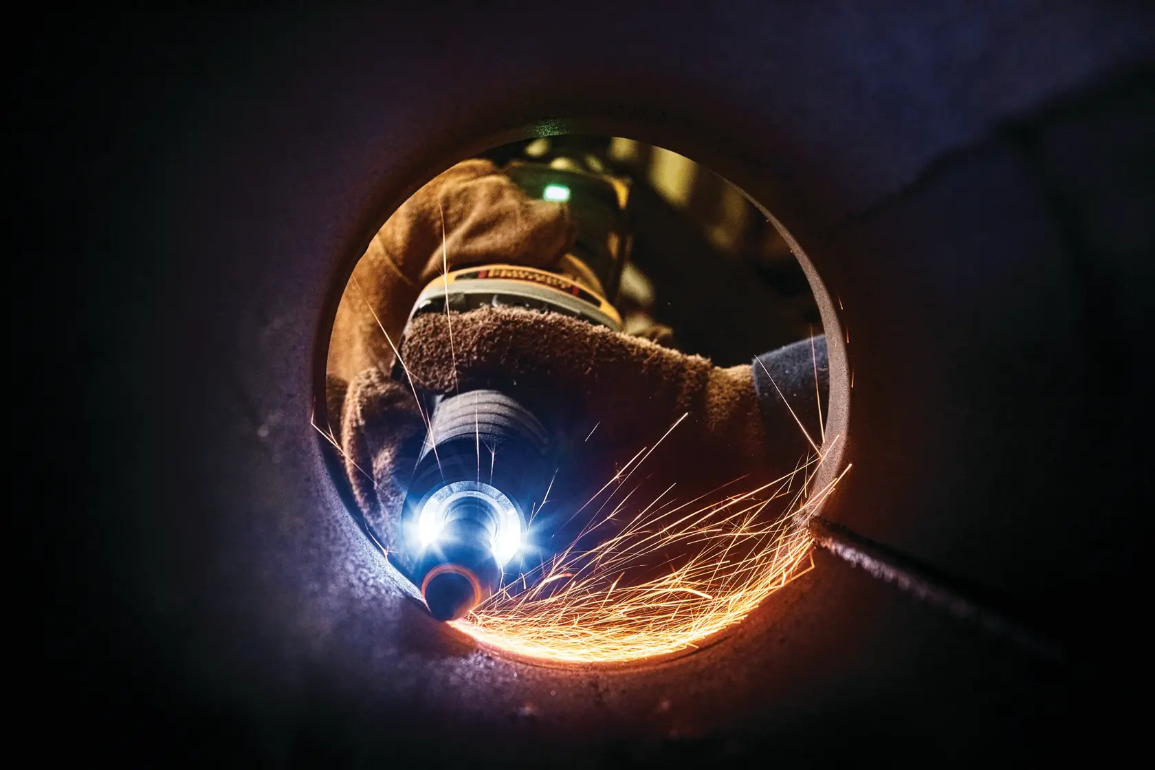 Nahaufnahme: DEWALT-Schleifer erzeugt Funken im Inneren eines Metallrohrs.