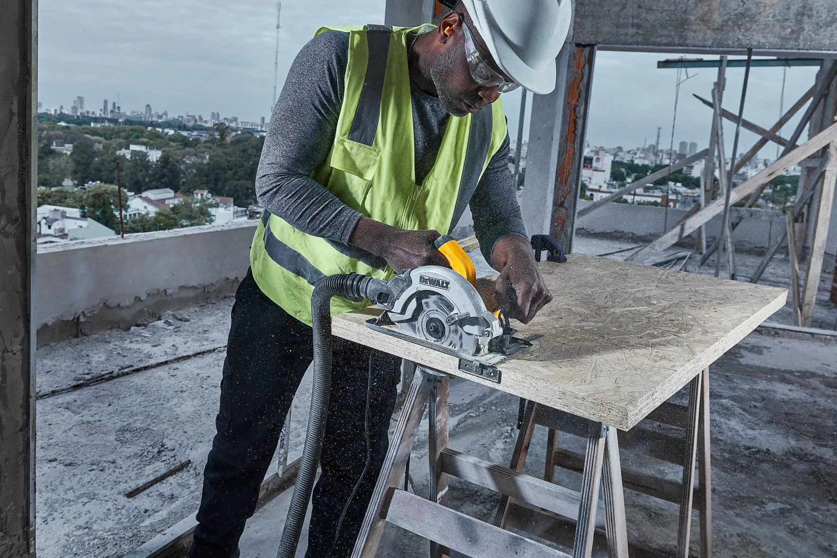 Ein Bauarbeiter mit Sicherheitsweste und Helm verwendet eine DEWALT DWE5615 Kreissäge, um ein Holzbrett auf einer Baustelle zu schneiden.