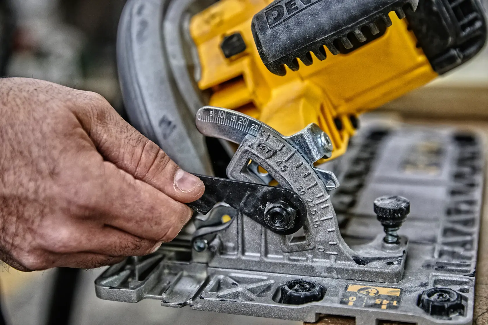 Hand justiert den Winkel an einer gelben DEWALT Kreissäge für präzises Holzarbeiten.