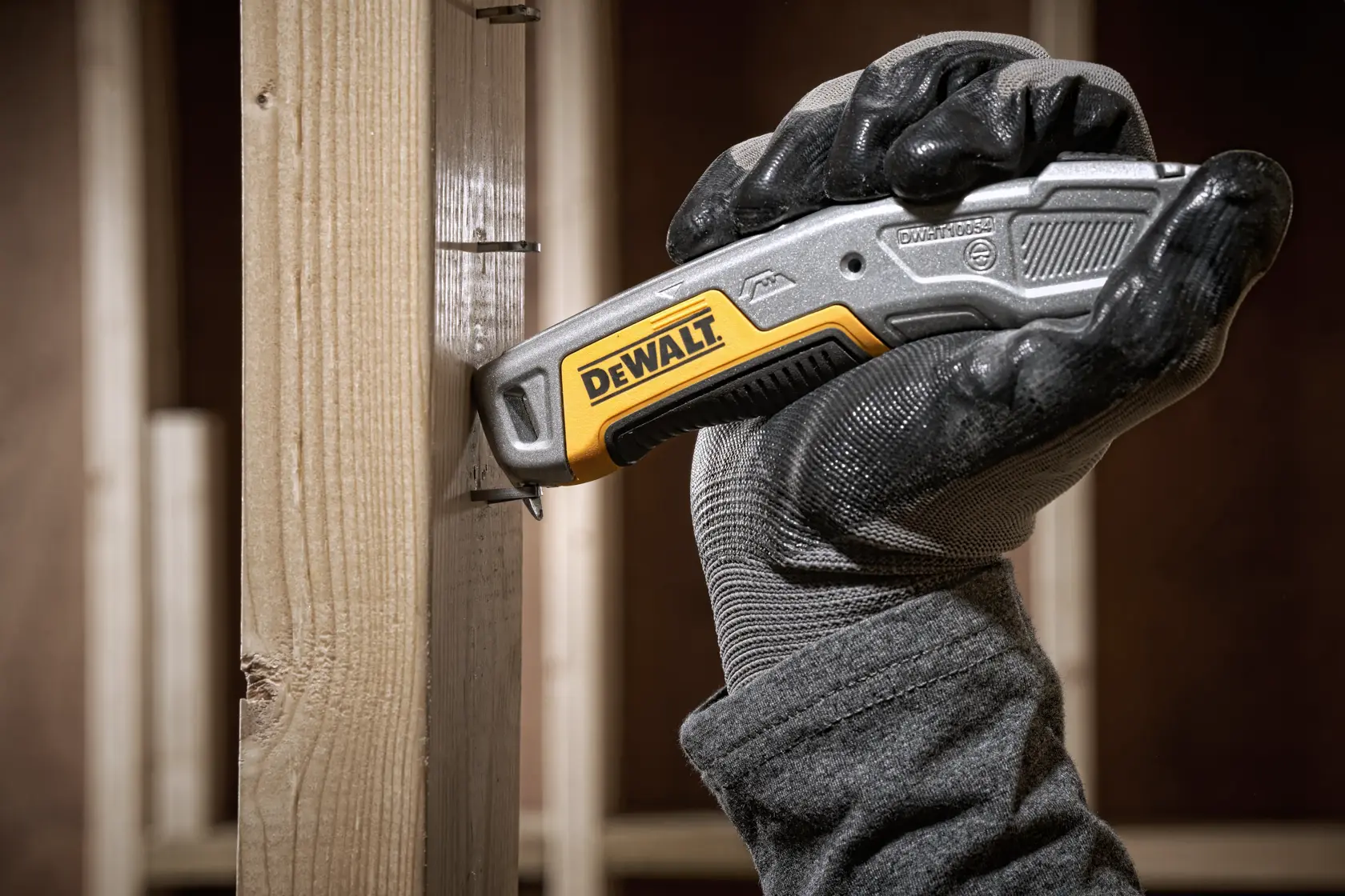 Ein DEWALT Universalmesser mit einziehbarer Klinge, silbernem Gehäuse und gelben sowie schwarzen Akzenten. Das DEWALT-Logo ist am Griff zu sehen.