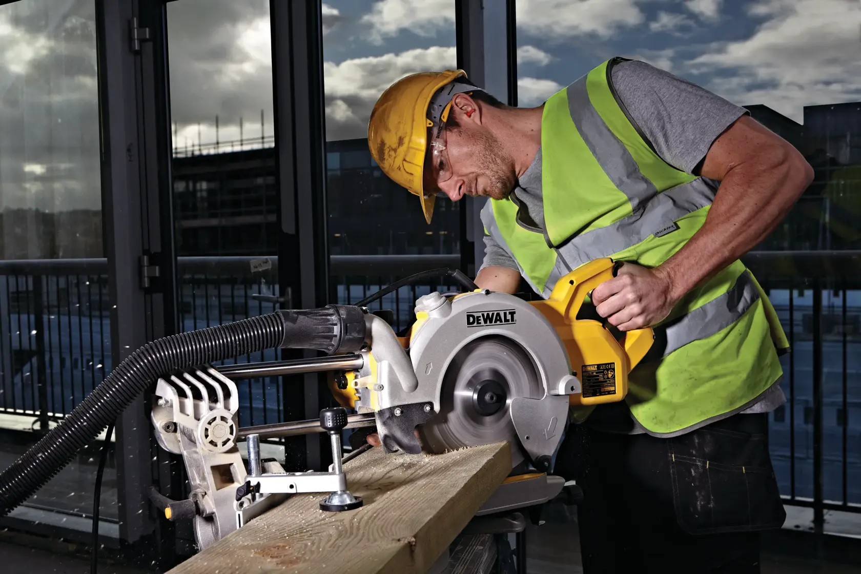 Arbeiter schneidet Holz mit DEWALT DWS778 auf Baustelle, trägt Sicherheitsausrüstung und Warnweste.