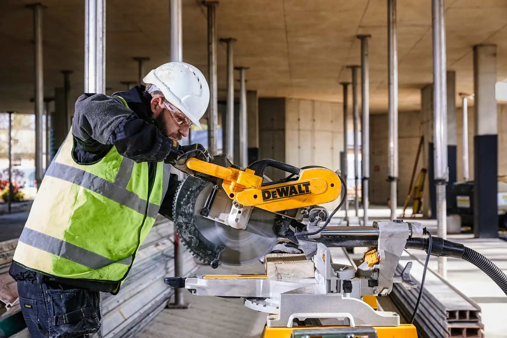 DEWALT DWS780, DWS780KIT Säge im Einsatz auf Baustelle. Arbeiter mit Schutzkleidung. Kategorie Fotografie.