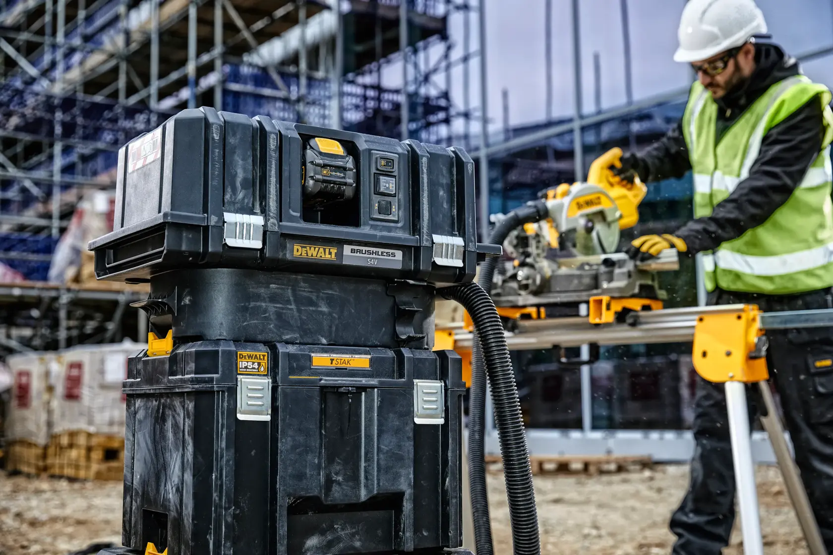 DEWALT Werkzeuglager und Staubsauger auf Baustelle, Arbeiter nutzt ein Elektrowerkzeug.
